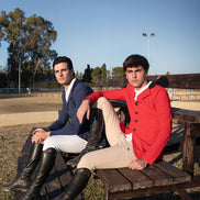 Two men sitting on a wooden bench outdoors with clear blue sky.