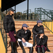 Four people in equestrian attire sitting on steps outdoors