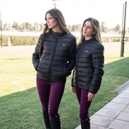 Two women wearing black puffer jackets and purple leggings standing on a sidewalk.