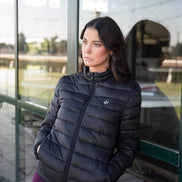 Woman wearing a black puffer jacket standing by a glass door.