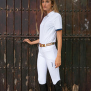 Woman in equestrian attire standing in front of a rustic wooden door.
