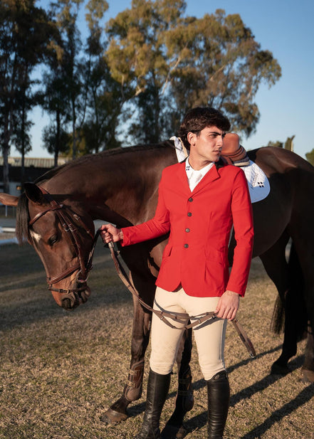 Man in a red jacket standing next to a horse in an outdoor setting