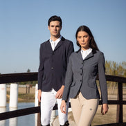 Two people in equestrian attire standing on a bridge with a clear blue sky.