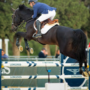 Horse and rider jumping over an obstacle at a equestrian event with 'Longines' branding.