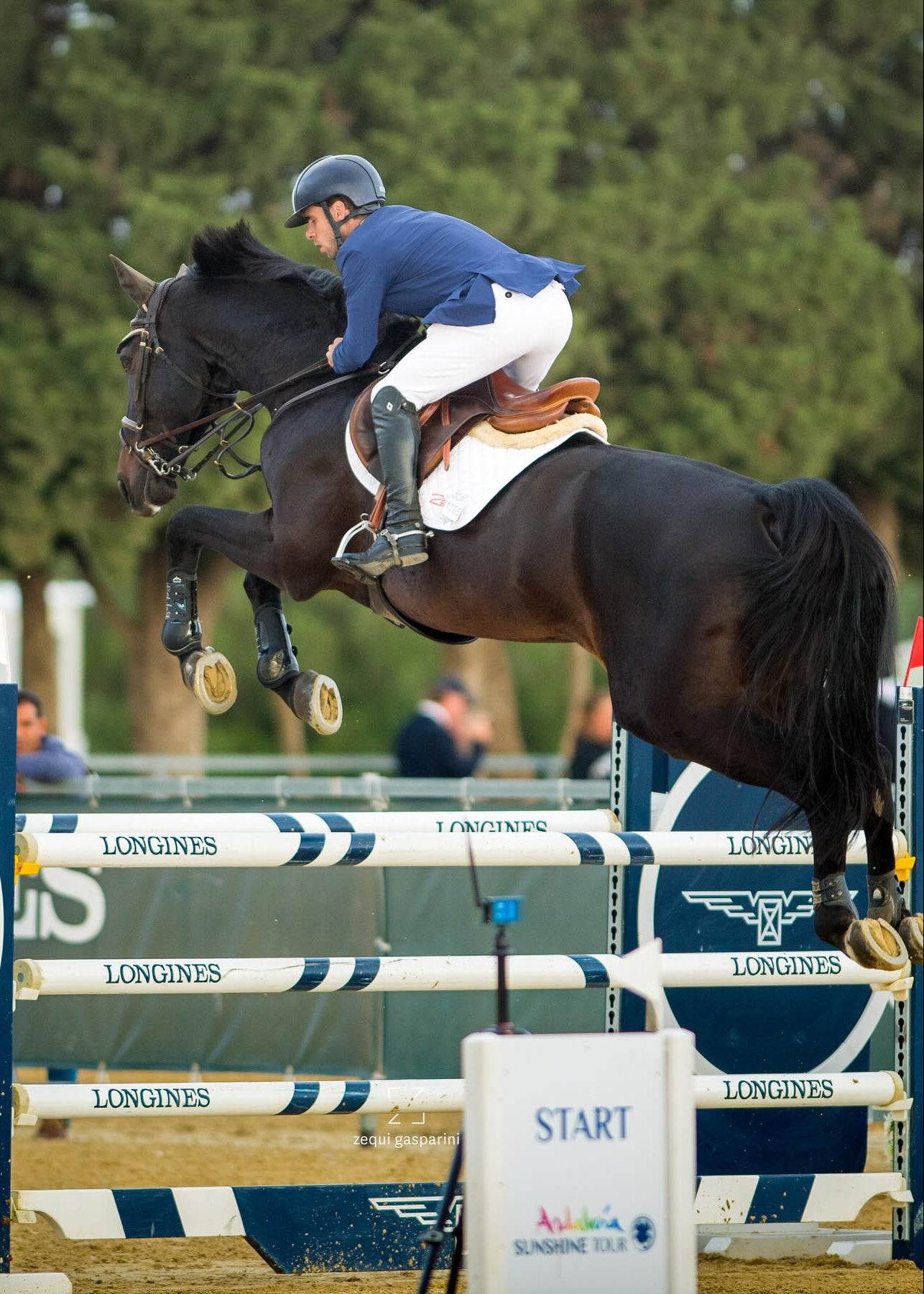 Horse and rider jumping over an obstacle at a equestrian event with 'Longines' branding.