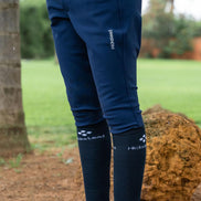 Navy riding pants with white text on a person standing outdoors.