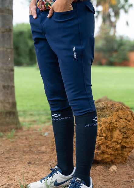 Navy riding pants with white text on a person standing outdoors.