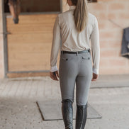 Person wearing equestrian attire in a stable setting