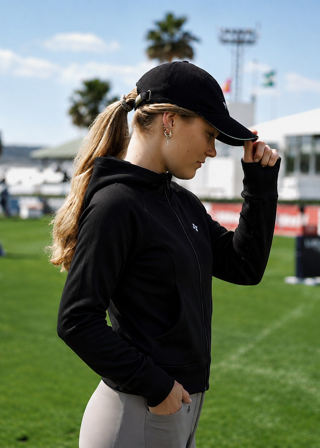 Person wearing a black cap and black jacket on a sports field