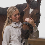 Woman petting a brown horse with a white blaze on its face.