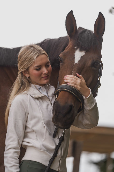 Woman petting a brown horse with a white blaze on its face.