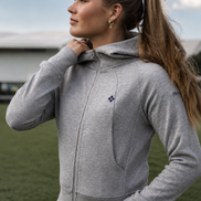 Woman wearing a gray hoodie with a brand logo outdoors