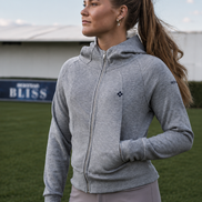 Woman wearing a gray hoodie and light purple pants on a sports field with a blurred background
