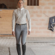 Woman in equestrian attire standing in a stable.