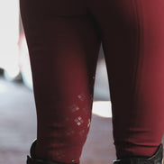 Maroon leggings with a subtle pattern worn with black boots on a blurred background