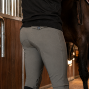 Person wearing equestrian pants and gloves in a stable