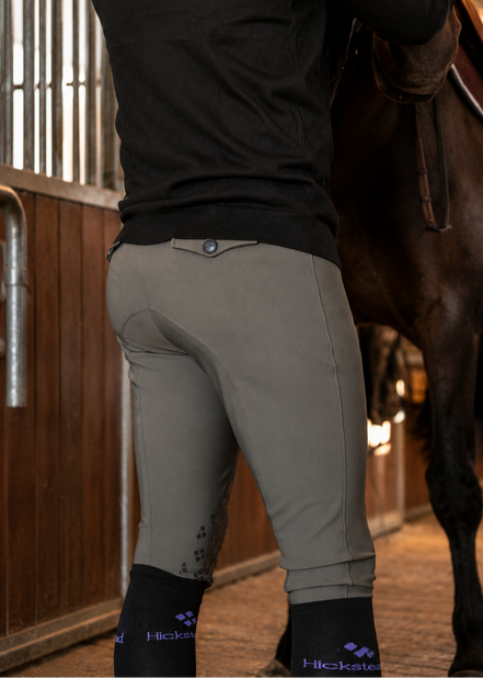 Person wearing equestrian pants and gloves in a stable