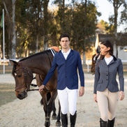 Two equestrian riders in formal riding attire walking with a horse on a gravel path.