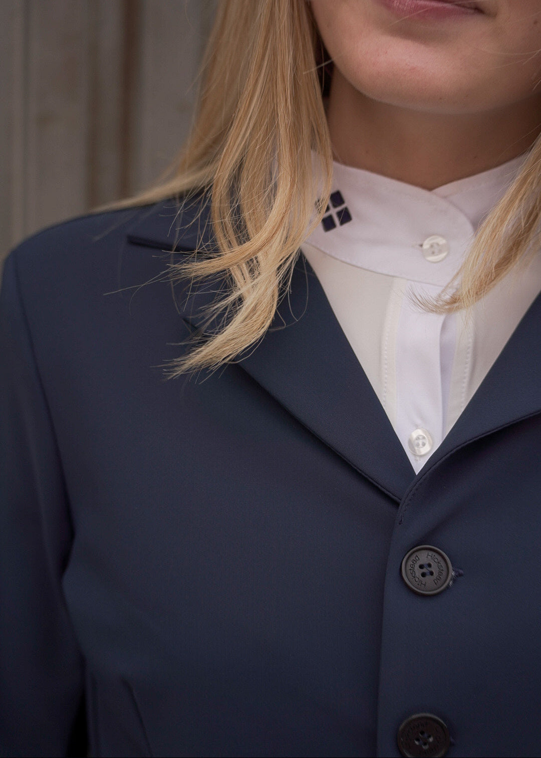 Person wearing a navy blazer over a white shirt with visible buttons.