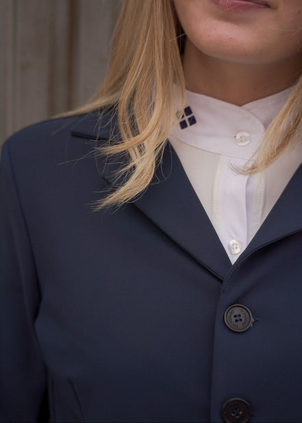 Person wearing a navy blazer over a white shirt with visible buttons.