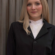 Woman wearing a black coat over a white shirt against a neutral background