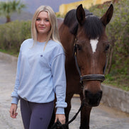 Woman walking a horse on a path with mountains in the background