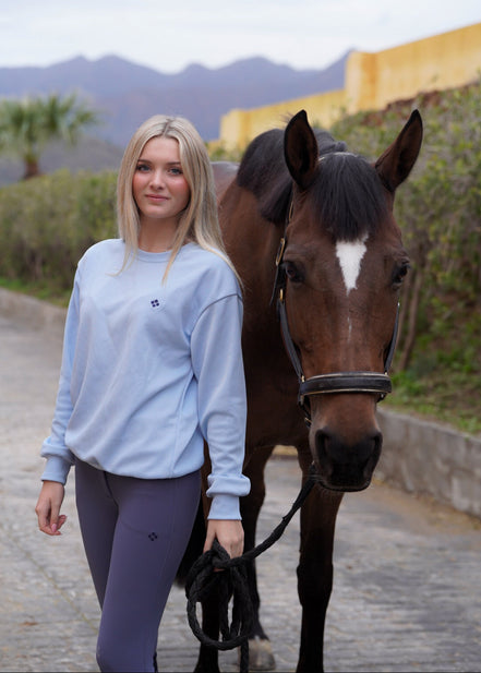 Woman walking a horse on a path with mountains in the background