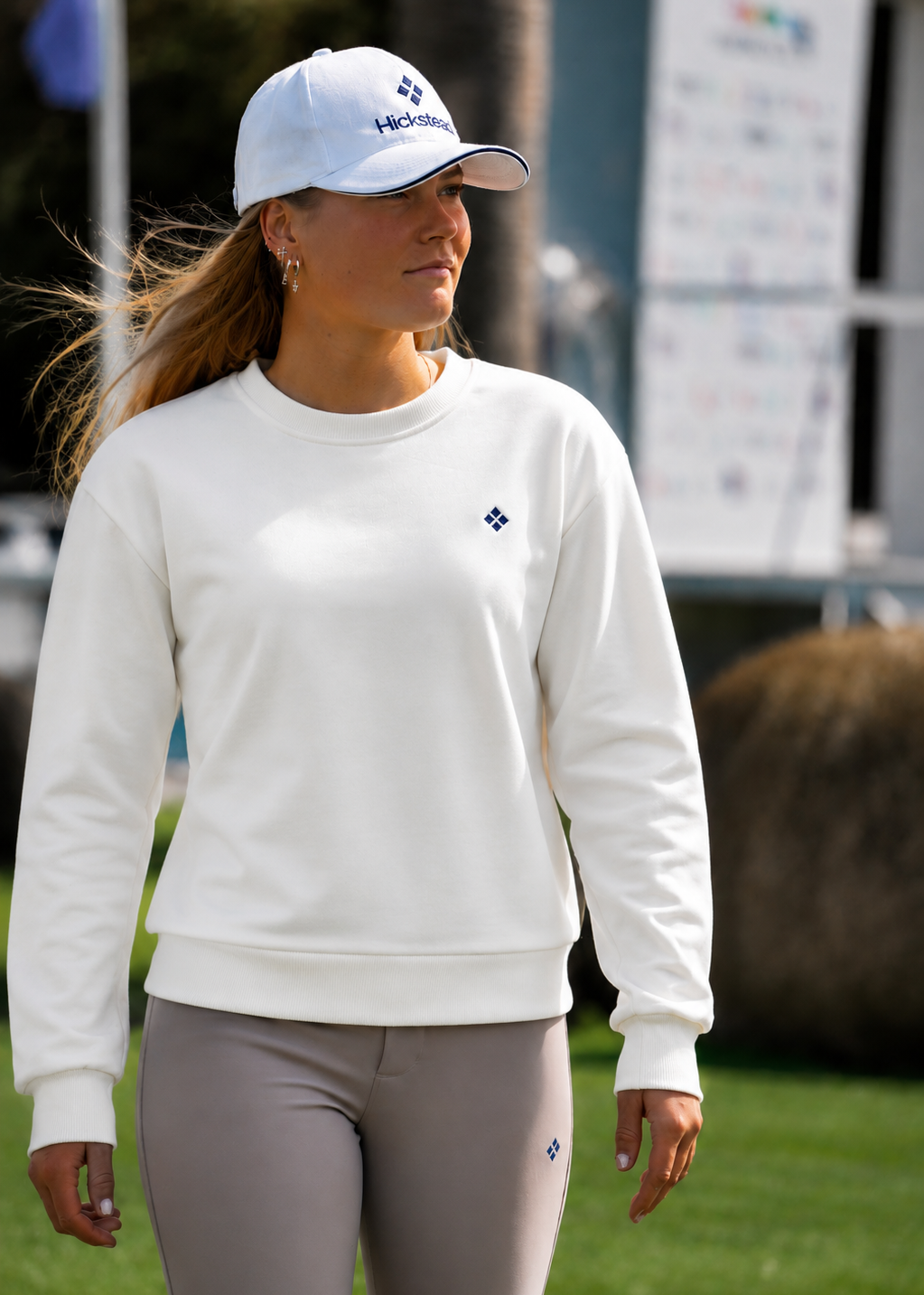 Woman wearing a white sweatshirt and cap on a golf course