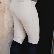 Person wearing beige riding pants against a stone wall.