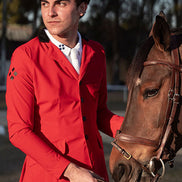 Man in a red jacket standing next to a brown horse outdoors